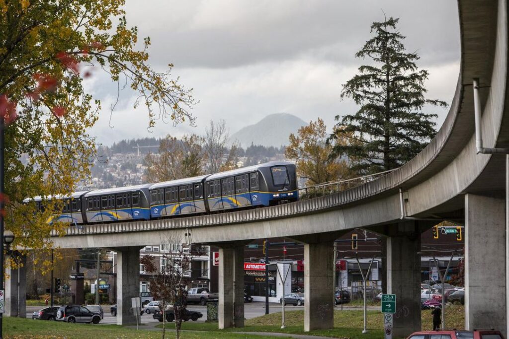 skytrain on the supported rails. below the skytrain there is a green area is visible. skytrain is the most popular Public Transit in Vancouver